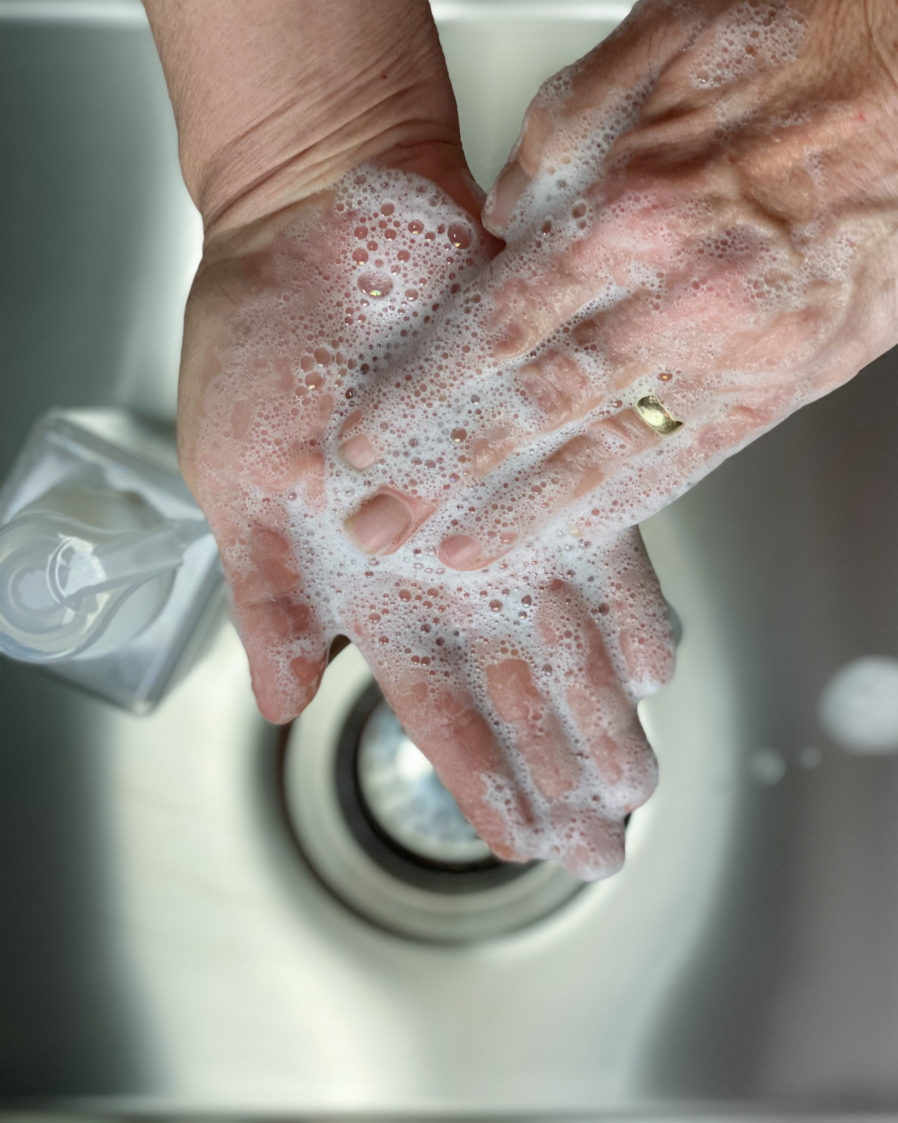 Woman washing hands over a sink with foaming hand wash