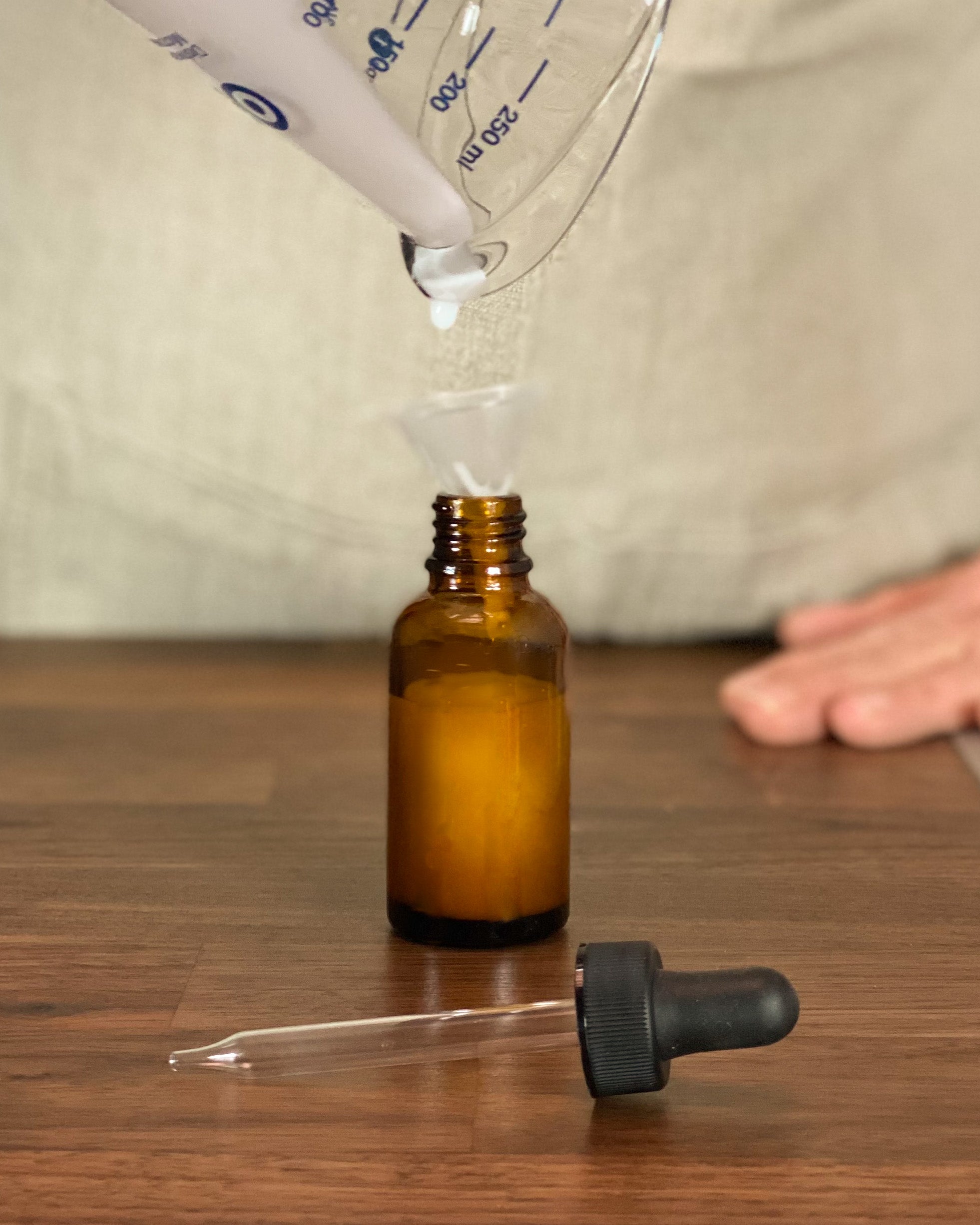 Pouring Milky Moisture Serum with a pitcher into a bottle with dropper.